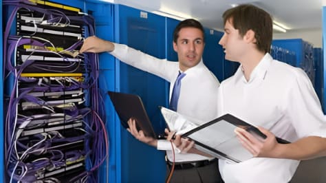 Two men discussing IT network deployment in front of a data rack